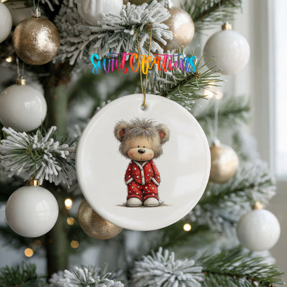 teddy bear wearing red Christmas pajamas ceramic Christmas ornament hanging on a frosted tree with ornaments