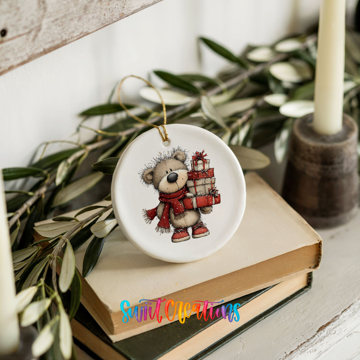 teddy bear in a red scarf carrying Christmas gifts ceramic Christmas ornament styled on stacked books with greenery