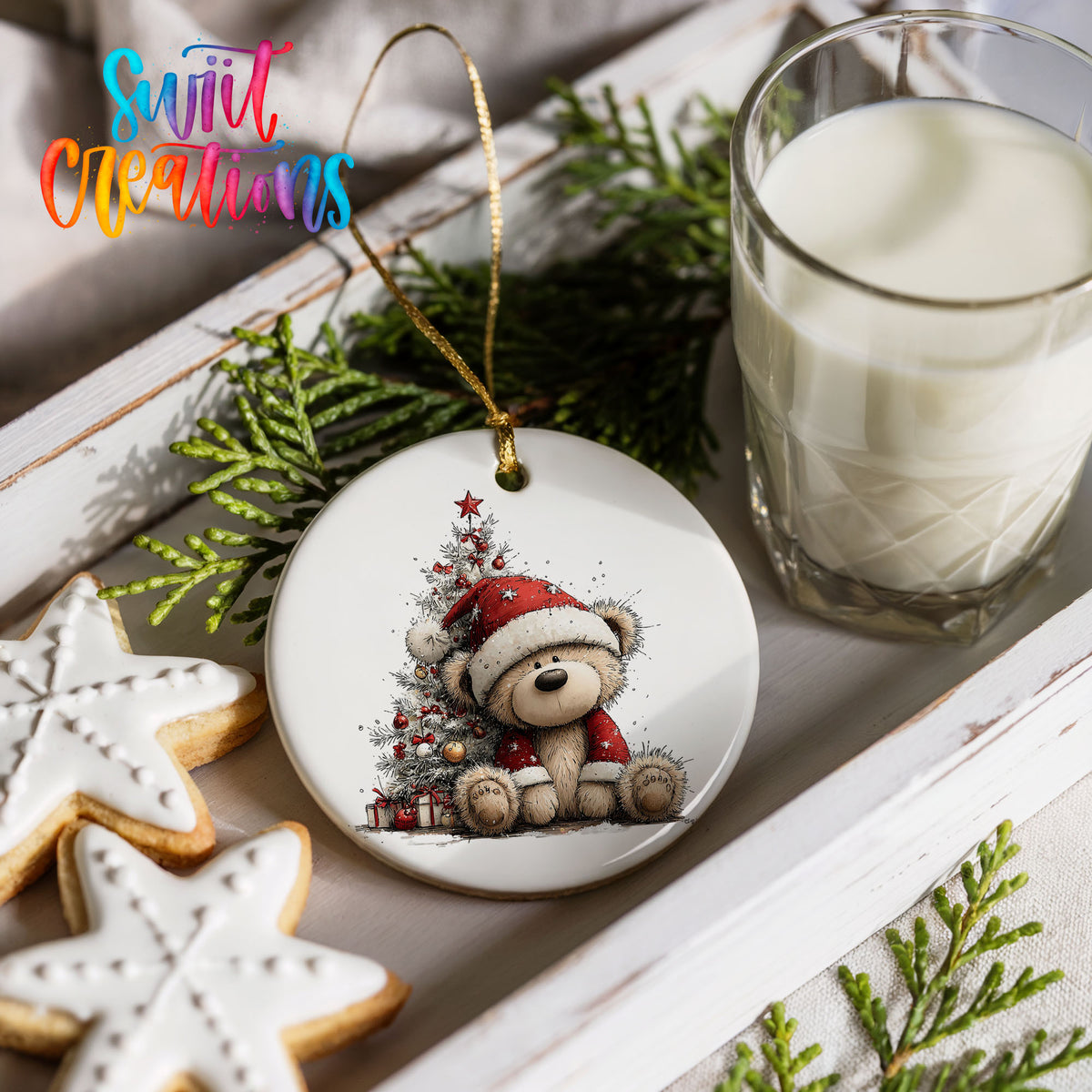 teddy bear sitting beside a decorated Christmas tree ceramic Christmas ornament styled with holiday cookies and a candle
