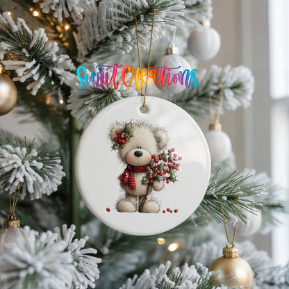 teddy bear with holly and red berries ceramic Christmas ornament hanging on a frosted Christmas tree