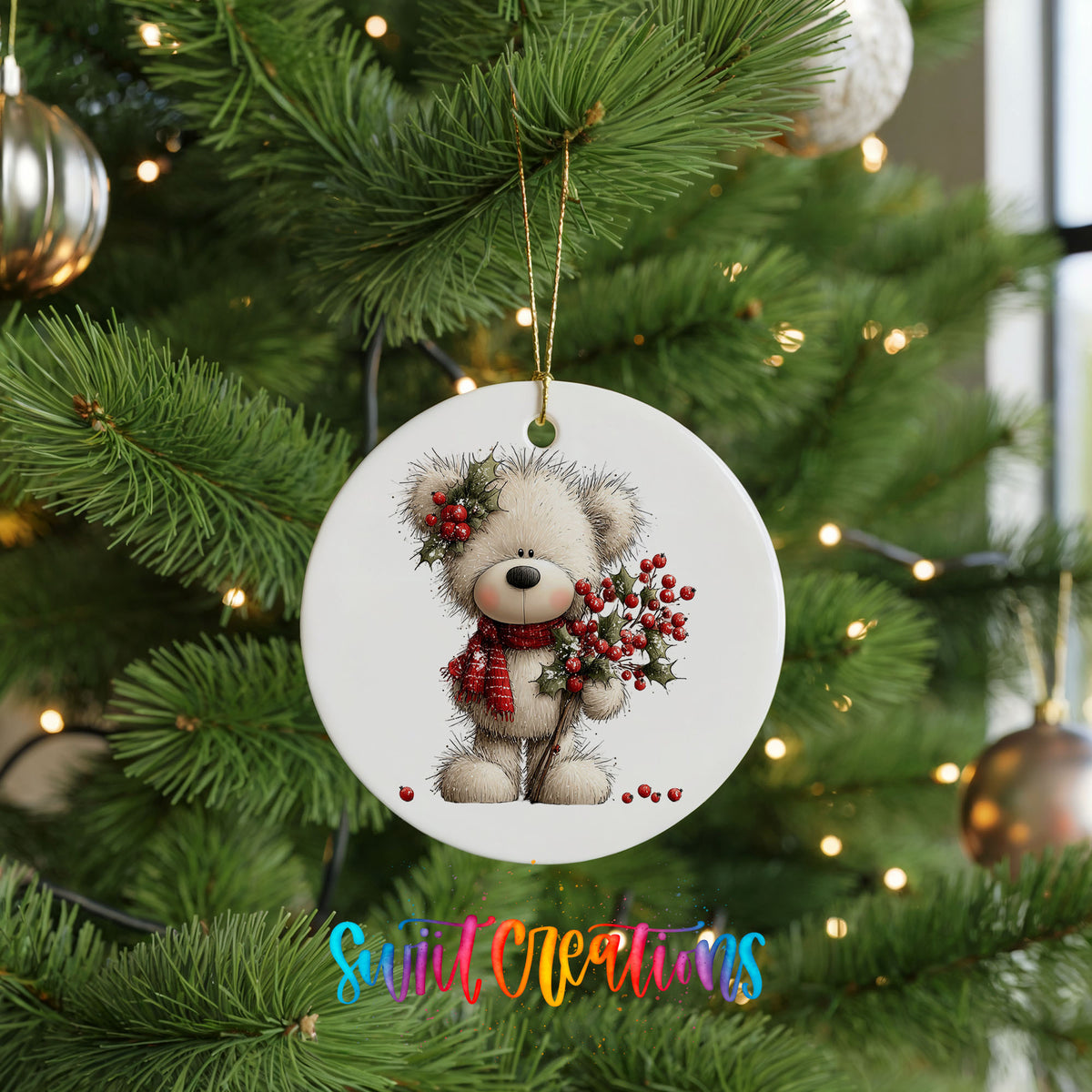teddy bear with holly and red berries ceramic Christmas ornament hanging on a lit Christmas tree