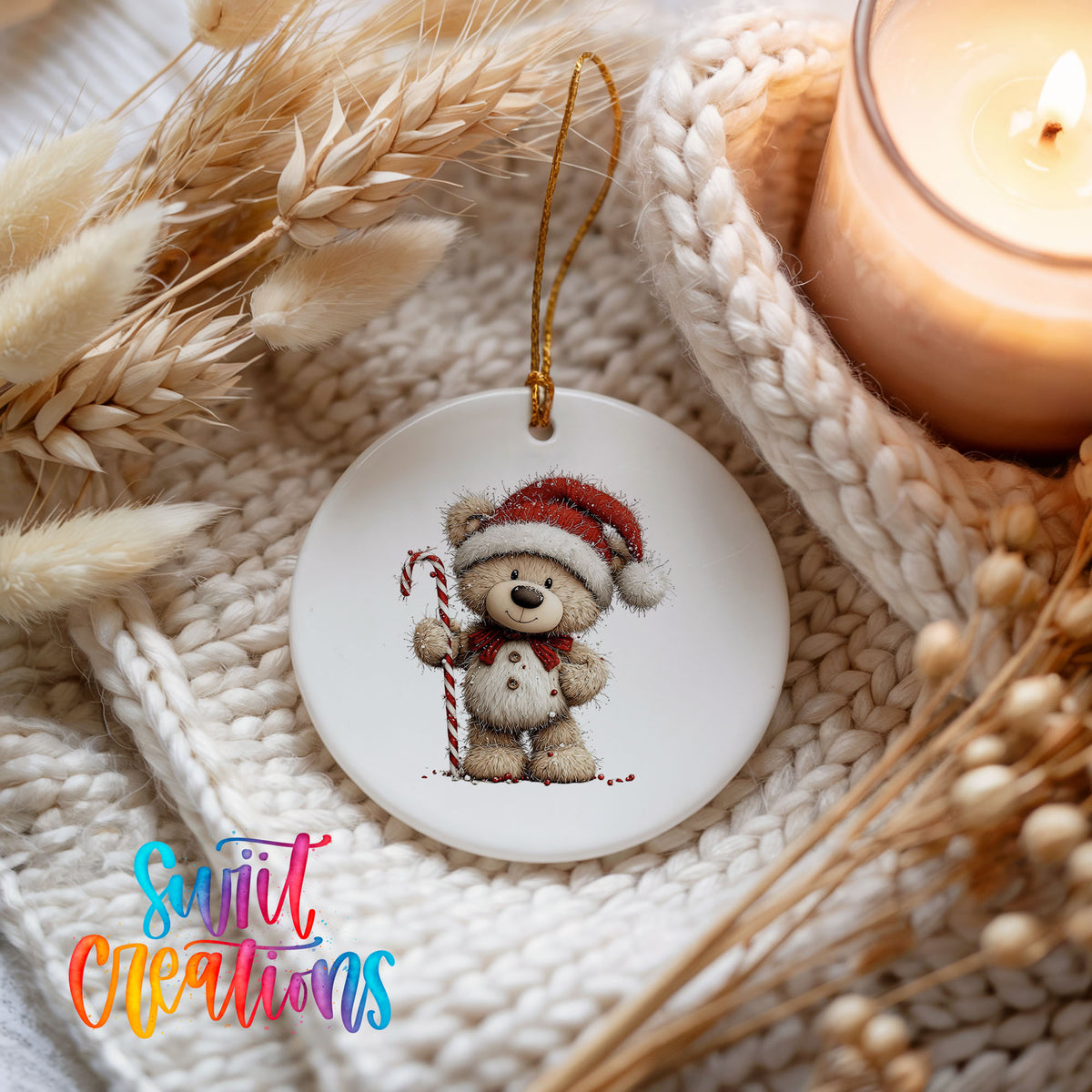 teddy bear wearing a Santa hat and holding a candy cane ceramic Christmas ornament styled on a cozy knit blanket