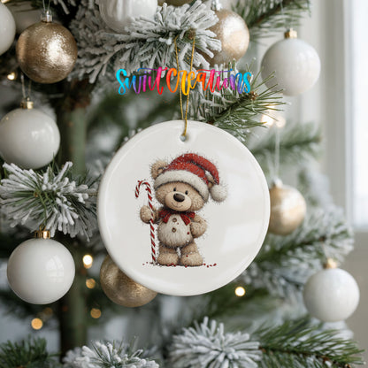 teddy bear wearing a Santa hat and holding a candy cane ceramic Christmas ornament hanging on a frosted tree with ornaments
