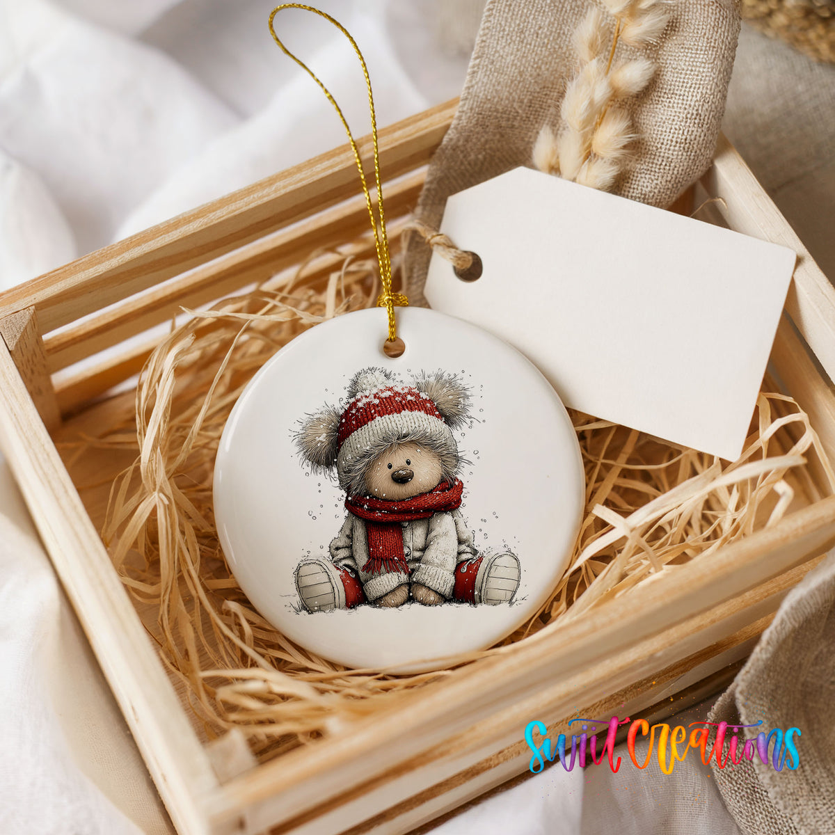 seated teddy bear in a red hat and scarf ceramic Christmas ornament displayed in a wooden gift crate