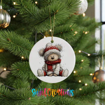 seated teddy bear in a red hat and scarf ceramic Christmas ornament hanging on a lit Christmas tree