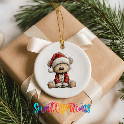 teddy bear in a Santa hat and red coat ceramic Christmas ornament displayed on a wrapped Christmas gift