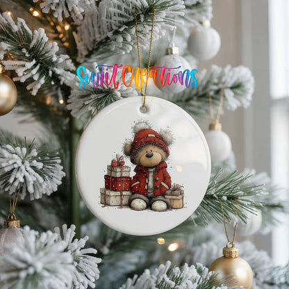 teddy bear in a red coat beside Christmas gifts ceramic Christmas ornament hanging on a frosted Christmas tree