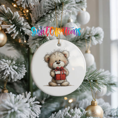 teddy bear holding a red Christmas gift ceramic Christmas ornament hanging on a frosted Christmas tree