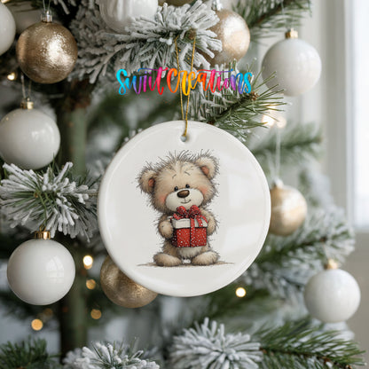 teddy bear holding a red Christmas gift ceramic Christmas ornament hanging on a frosted tree with ornaments