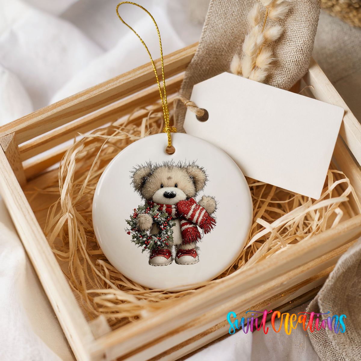 teddy bear with a red striped scarf and holly wreath ceramic Christmas ornament displayed in a wooden gift crate
