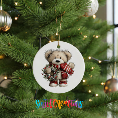 teddy bear with a red striped scarf and holly wreath ceramic Christmas ornament hanging on a lit Christmas tree