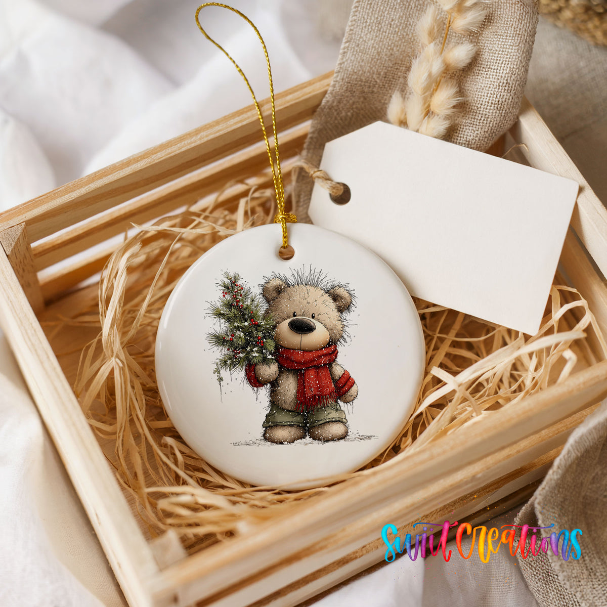 teddy bear in a red scarf holding a Christmas tree ceramic Christmas ornament displayed in a wooden gift crate