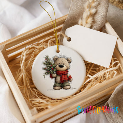 teddy bear in a red scarf holding a Christmas tree ceramic Christmas ornament displayed in a wooden gift crate