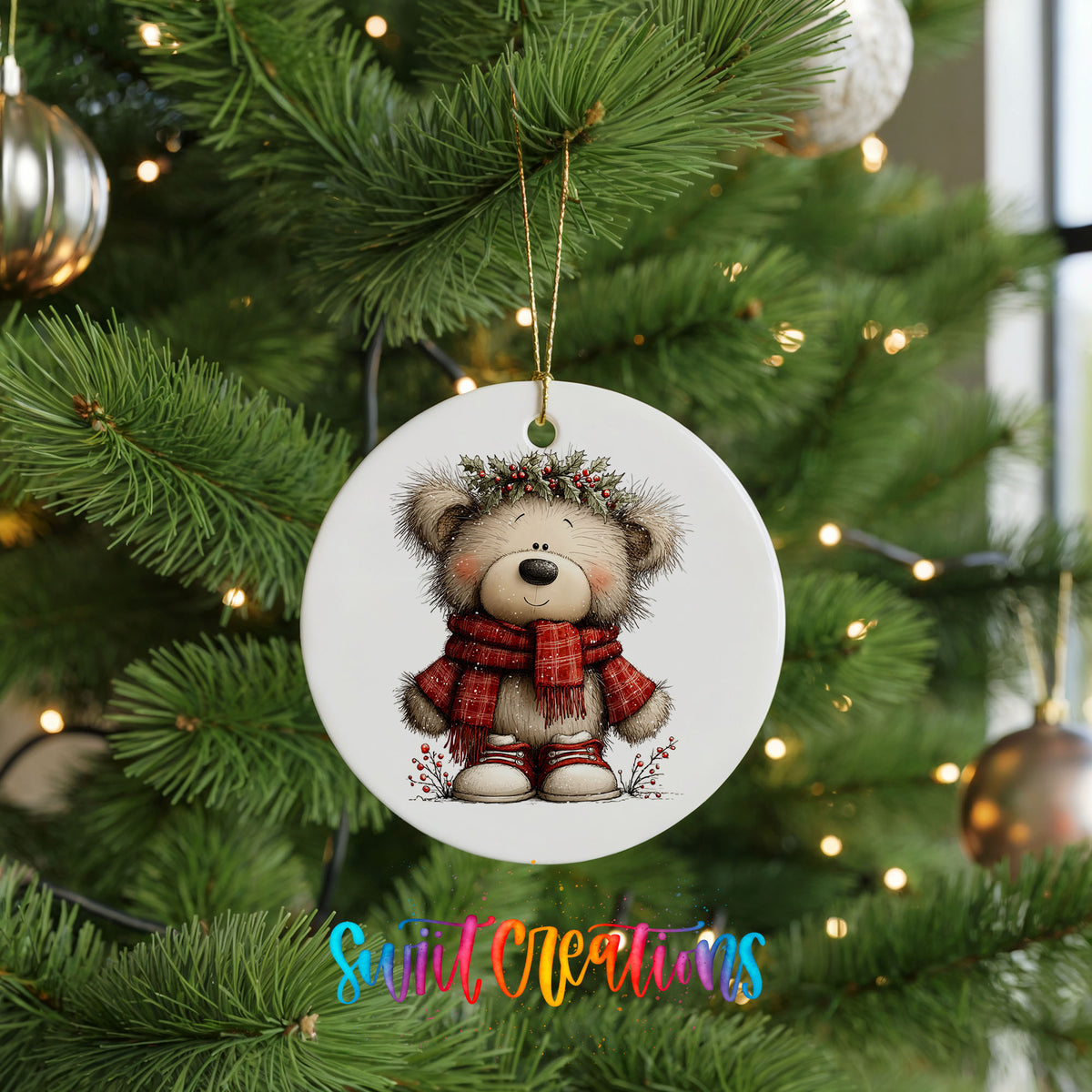 teddy bear in a red plaid scarf with holly ceramic Christmas ornament hanging on a lit Christmas tree