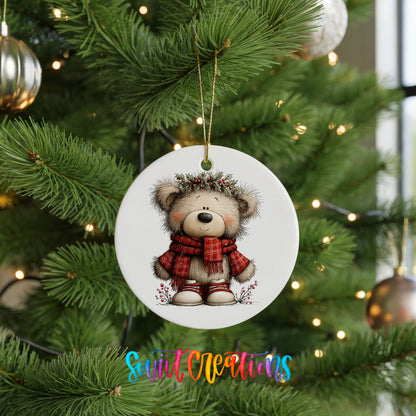 teddy bear in a red plaid scarf with holly ceramic Christmas ornament hanging on a lit Christmas tree