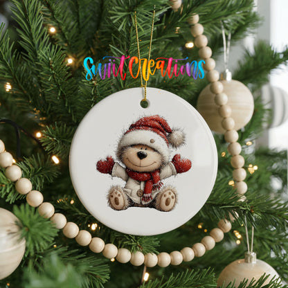 seated teddy bear in a Santa hat and red scarf ceramic Christmas ornament hanging on a green Christmas tree