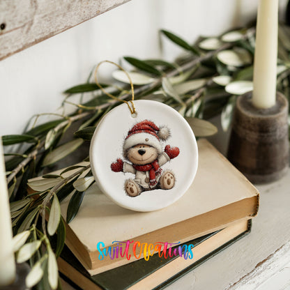 seated teddy bear in a Santa hat and red scarf ceramic Christmas ornament styled on stacked books with greenery