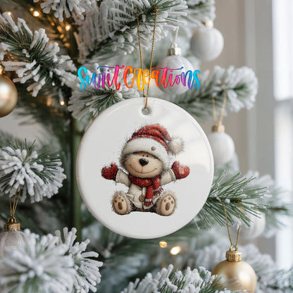 seated teddy bear in a Santa hat and red scarf ceramic Christmas ornament hanging on a frosted Christmas tree