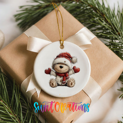 seated teddy bear in a Santa hat and red scarf ceramic Christmas ornament displayed on a wrapped Christmas gift