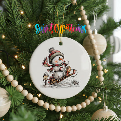 snowman riding a wooden sled ceramic Christmas ornament hanging on a green Christmas tree