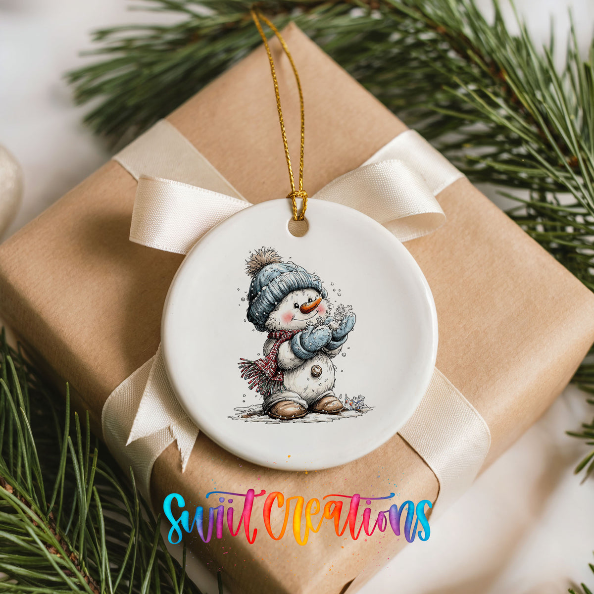 snowman in a blue hat holding a snowball ceramic Christmas ornament displayed on a wrapped Christmas gift