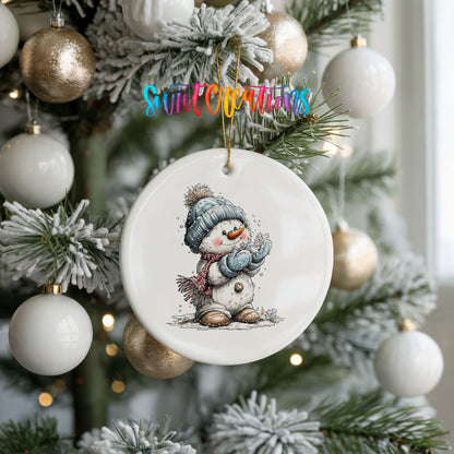 snowman in a blue hat holding a snowball ceramic Christmas ornament hanging on a frosted tree with ornaments