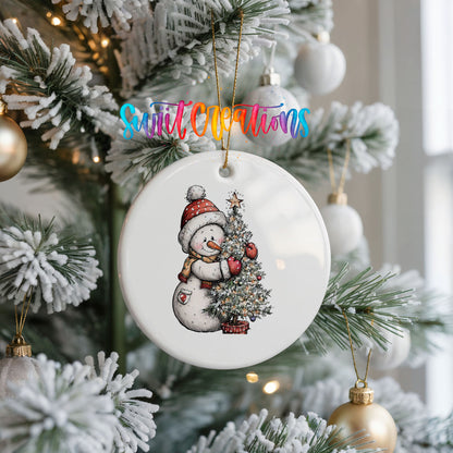 snowman decorating a snowy Christmas tree ceramic Christmas ornament hanging on a frosted Christmas tree