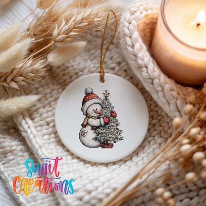 snowman decorating a snowy Christmas tree ceramic Christmas ornament styled on a cozy knit blanket