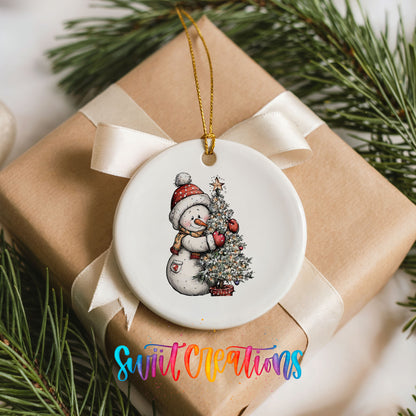 snowman decorating a snowy Christmas tree ceramic Christmas ornament displayed on a wrapped Christmas gift