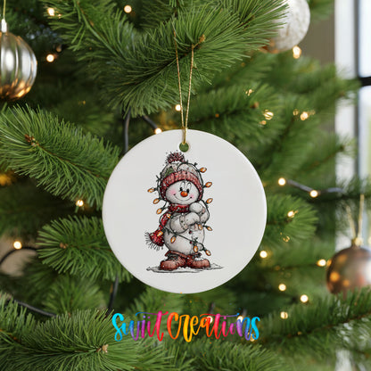 snowman in a red hat and striped scarf ceramic Christmas ornament hanging on a lit Christmas tree