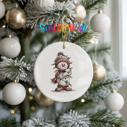 snowman in a red hat and striped scarf ceramic Christmas ornament hanging on a frosted tree with ornaments