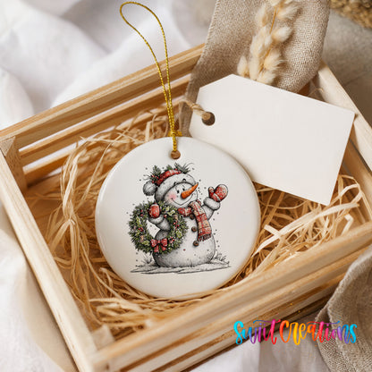 snowman in a red hat holding a Christmas ornament ceramic Christmas ornament displayed in a wooden gift crate
