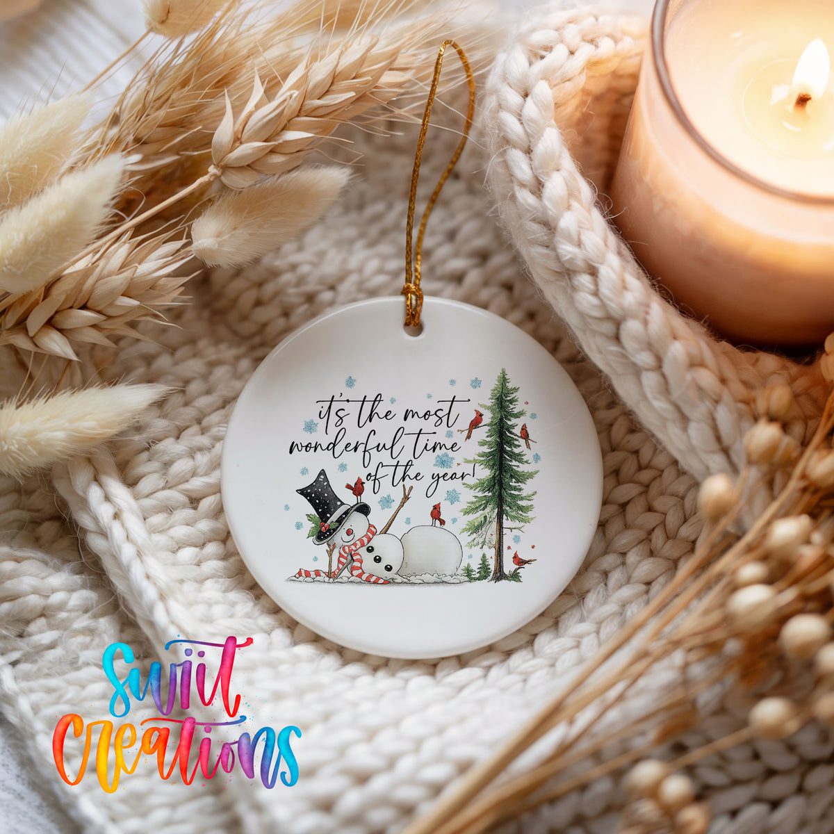 It's the Most Wonderful Time of the Year snowman design ceramic Christmas ornament styled on a cozy knit blanket