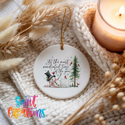 It's the Most Wonderful Time of the Year snowman design ceramic Christmas ornament styled on a cozy knit blanket