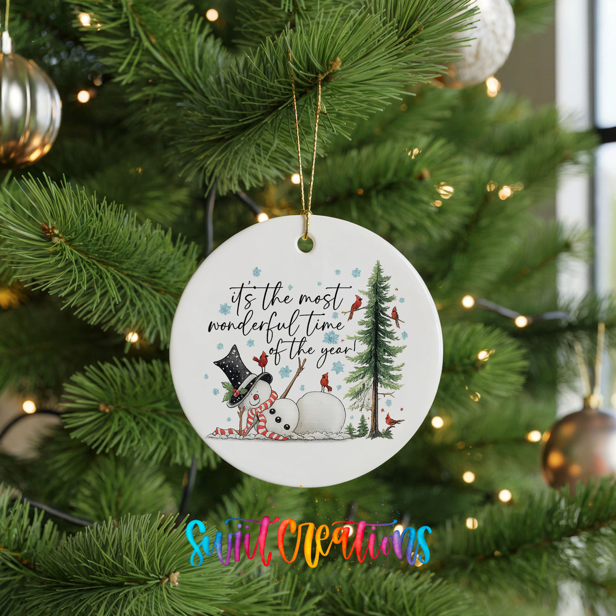 It's the Most Wonderful Time of the Year snowman design ceramic Christmas ornament hanging on a lit Christmas tree
