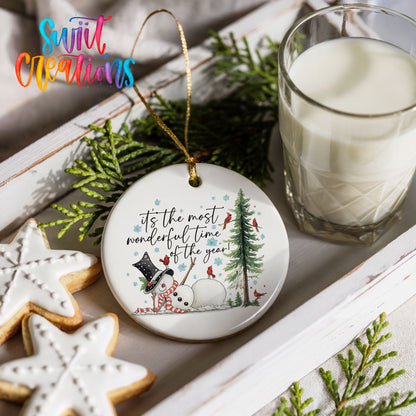 It's the Most Wonderful Time of the Year snowman design ceramic Christmas ornament styled with holiday cookies and a candle