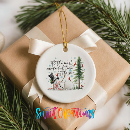 It's the Most Wonderful Time of the Year snowman design ceramic Christmas ornament displayed on a wrapped Christmas gift