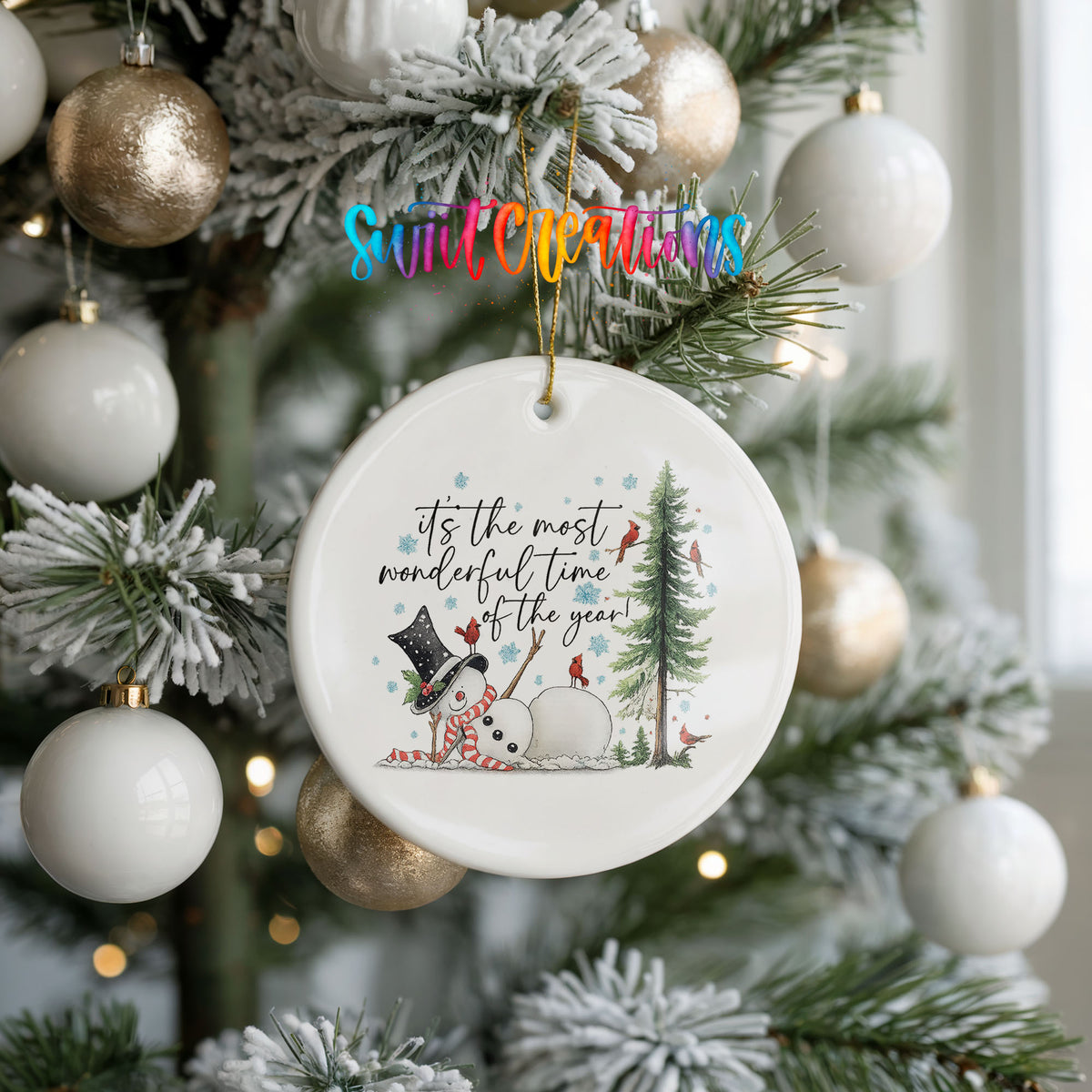 It's the Most Wonderful Time of the Year snowman design ceramic Christmas ornament hanging on a frosted tree with ornaments