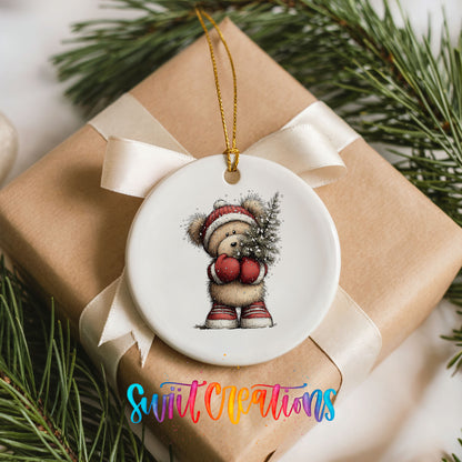 woodland bear in a Santa hat carrying a Christmas tree ceramic Christmas ornament displayed on a wrapped Christmas gift