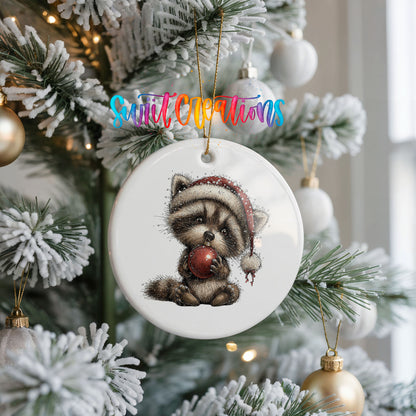 woodland raccoon in a Santa hat holding a red ornament ceramic Christmas ornament hanging on a frosted Christmas tree