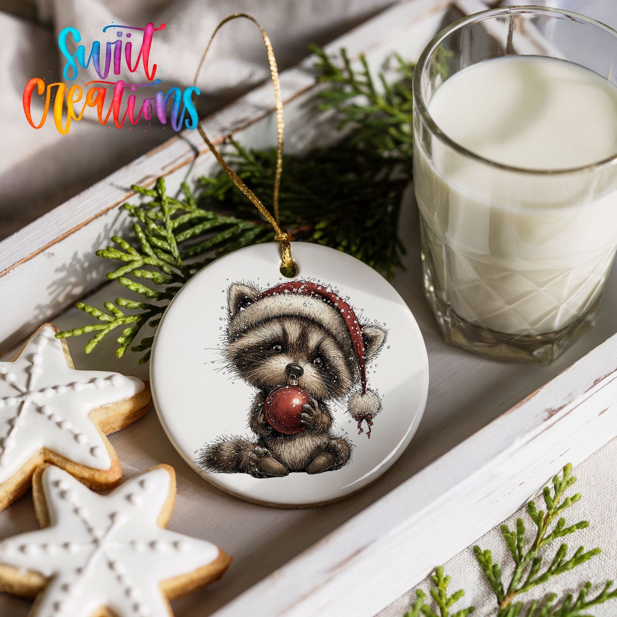 woodland raccoon in a Santa hat holding a red ornament ceramic Christmas ornament styled with holiday cookies and a candle