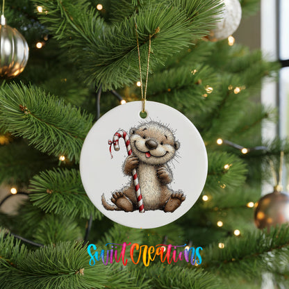 woodland otter holding a striped candy cane ceramic Christmas ornament hanging on a lit Christmas tree