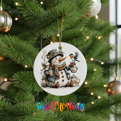 snowman with a lantern and winter birds ceramic Christmas ornament hanging on a lit Christmas tree