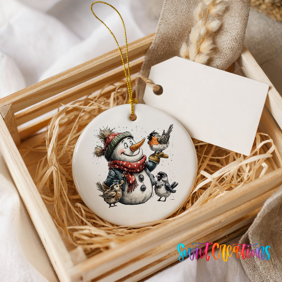 snowman in a red scarf surrounded by birds ceramic Christmas ornament displayed in a wooden gift crate