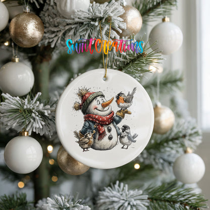 snowman in a red scarf surrounded by birds ceramic Christmas ornament hanging on a frosted tree with ornaments