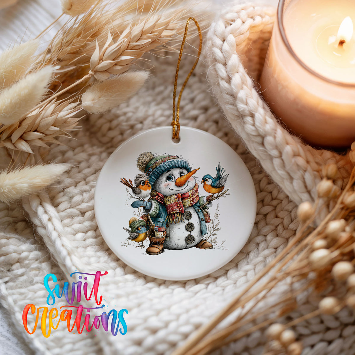 snowman in a blue hat with colorful winter birds ceramic Christmas ornament styled on a cozy knit blanket