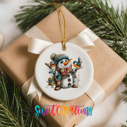 snowman in a blue hat with colorful winter birds ceramic Christmas ornament displayed on a wrapped Christmas gift