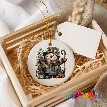 snowman with a walking stick and winter greenery ceramic Christmas ornament displayed in a wooden gift crate