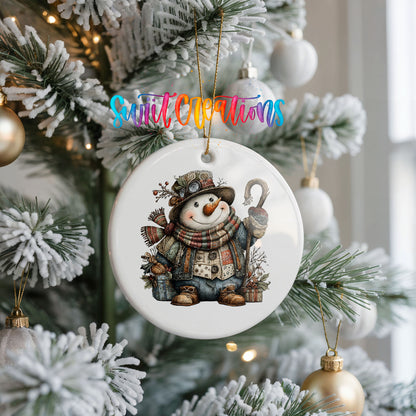 rustic snowman with a walking stick and plaid scarf ceramic Christmas ornament hanging on a frosted Christmas tree