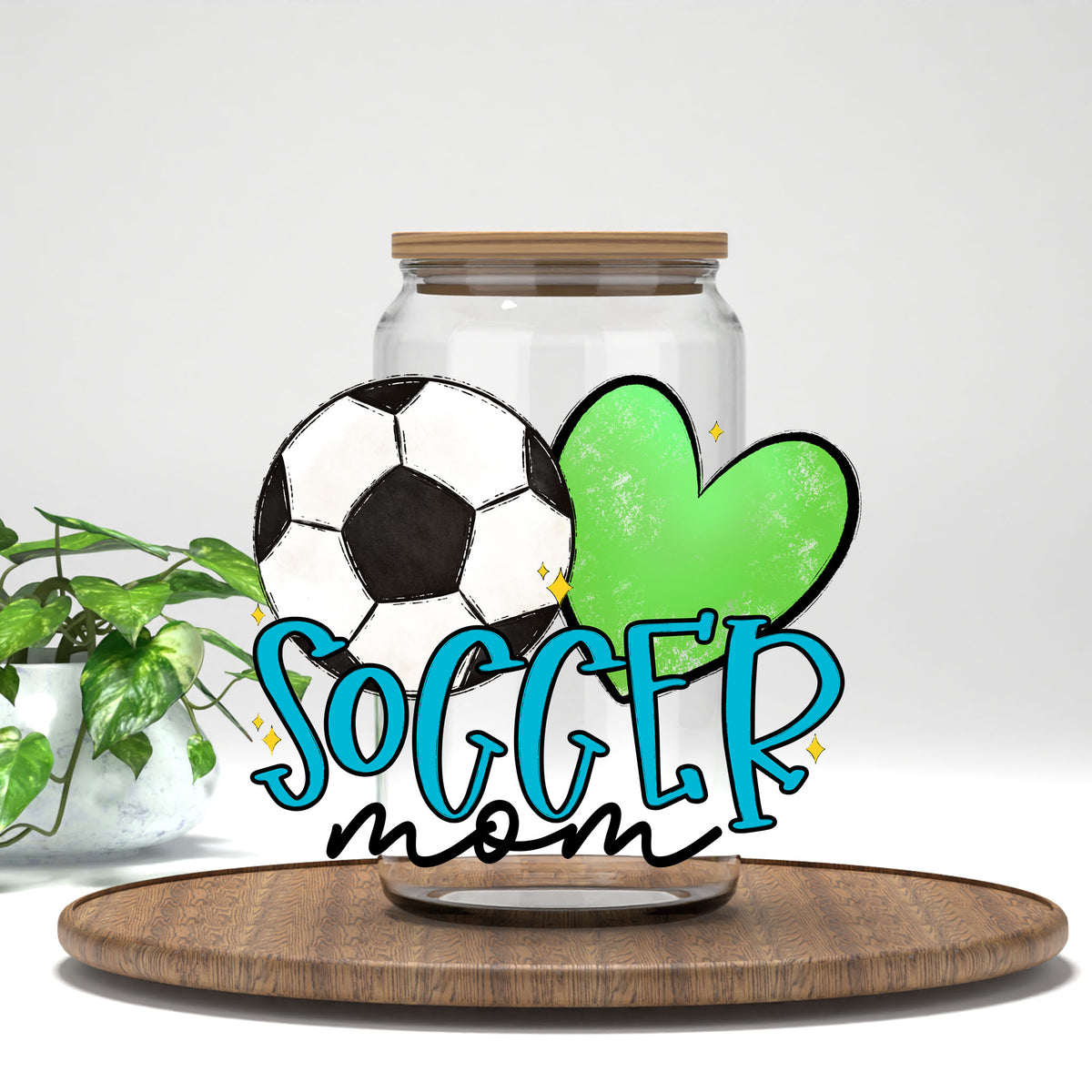 Soccer Mom blue letters and green heart UV DTF wrap on a clear glass can